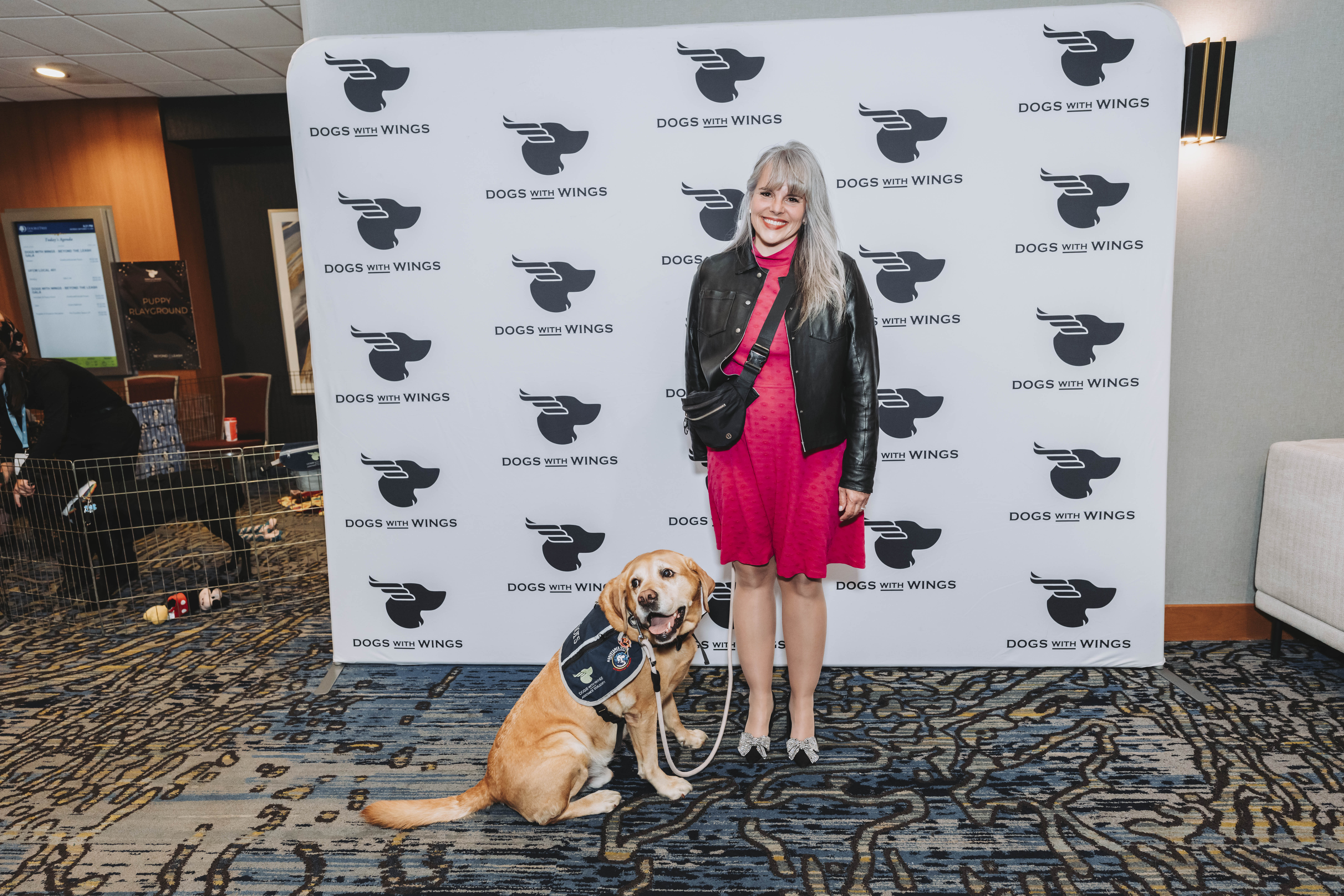 A guest in pink with a yellow Labrador in a service vest