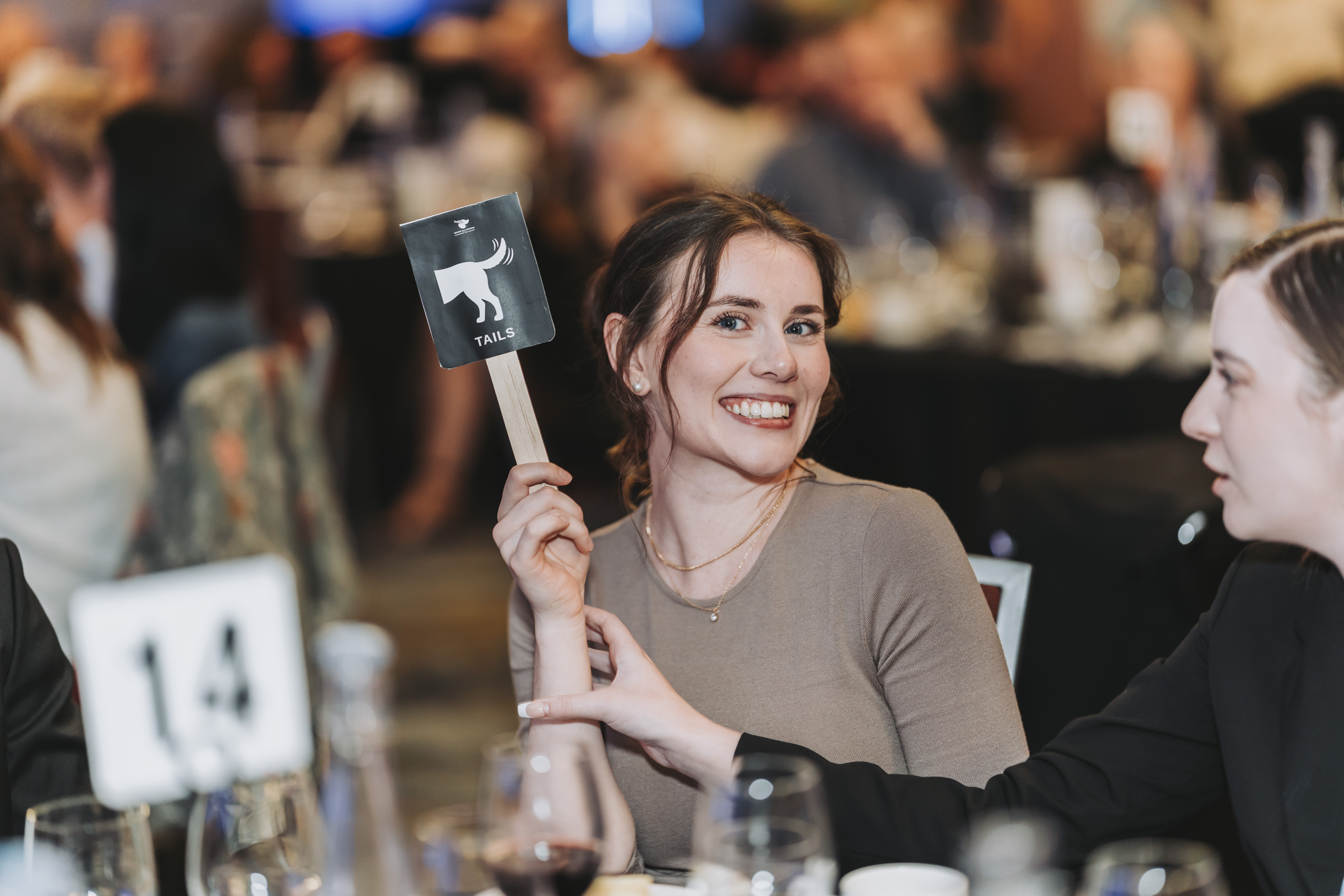 A guest holding up a Tails paddle at table fourteen