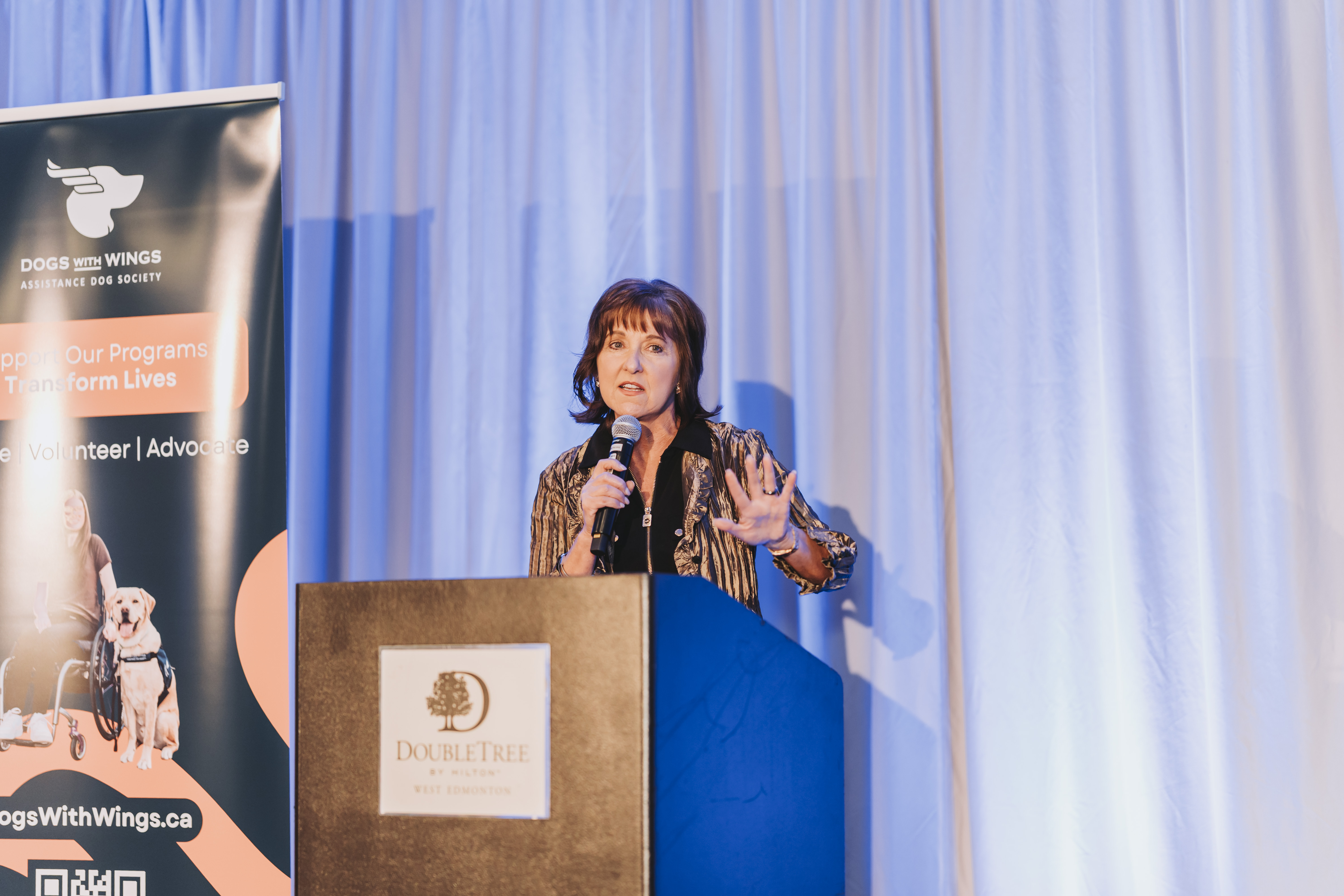 A guest speaking at the DoubleTree podium by the gala banner
