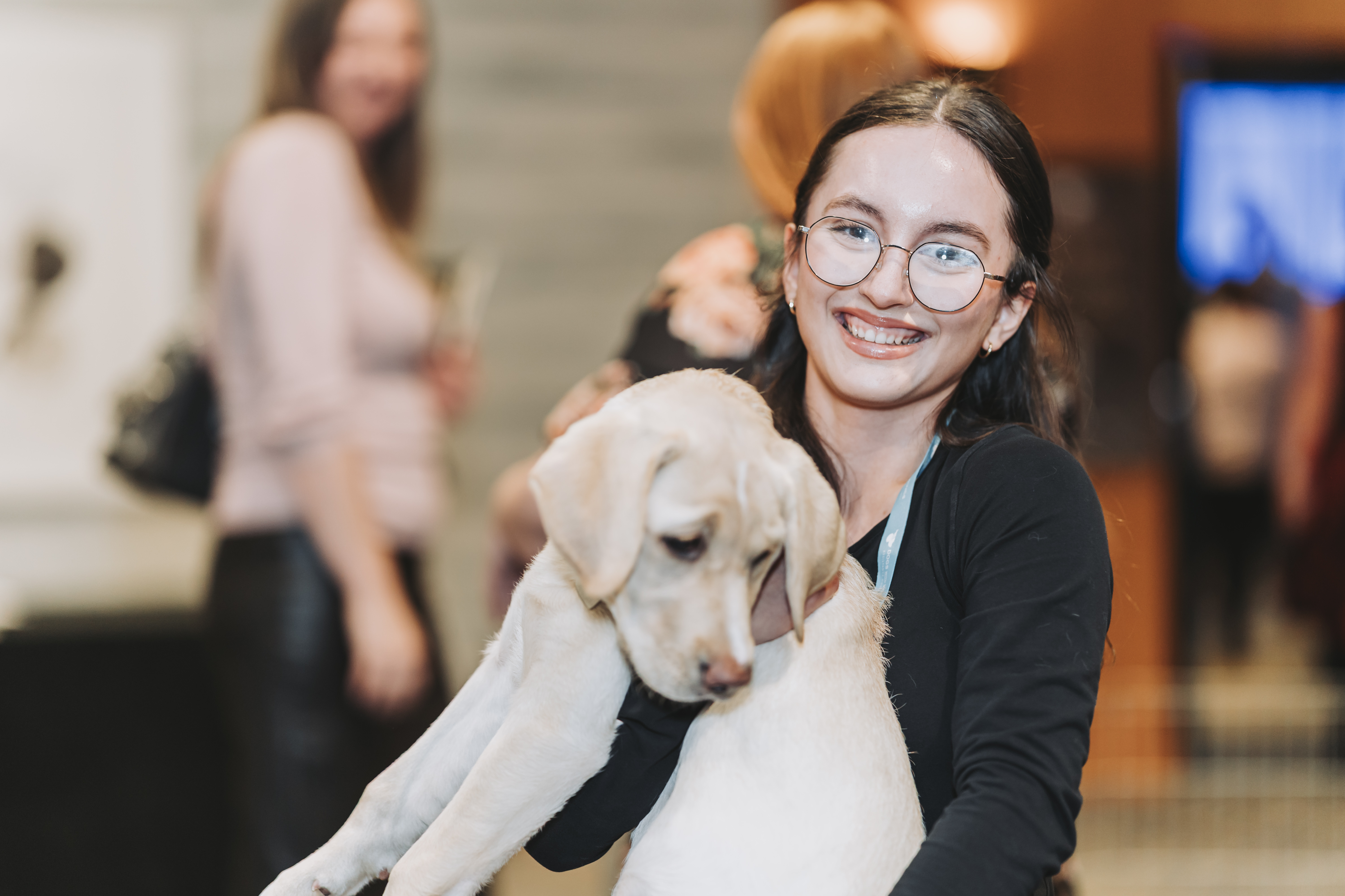 A guest in glasses holding a yellow Labrador puppy