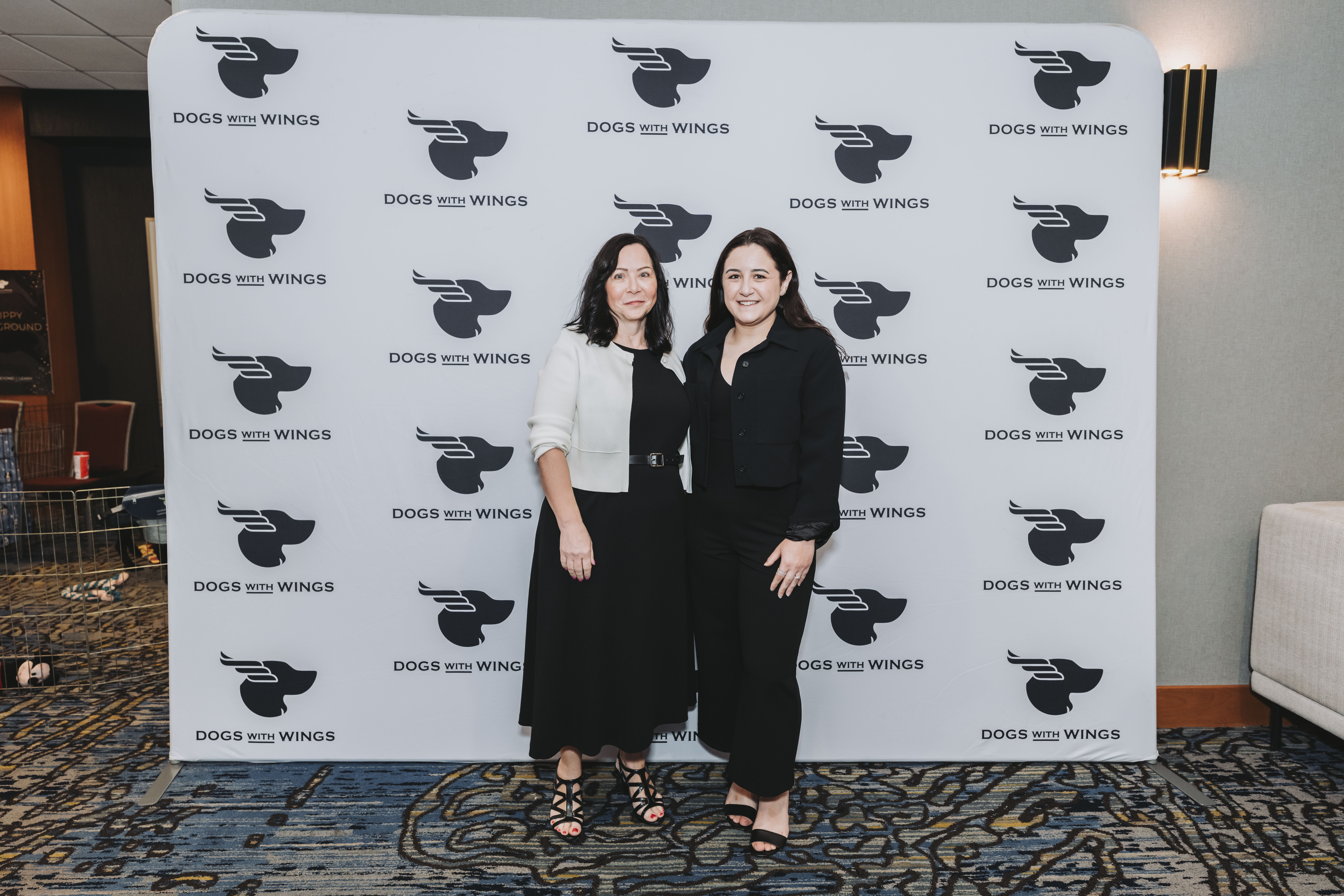 Two guests in black posing at the gala photo wall