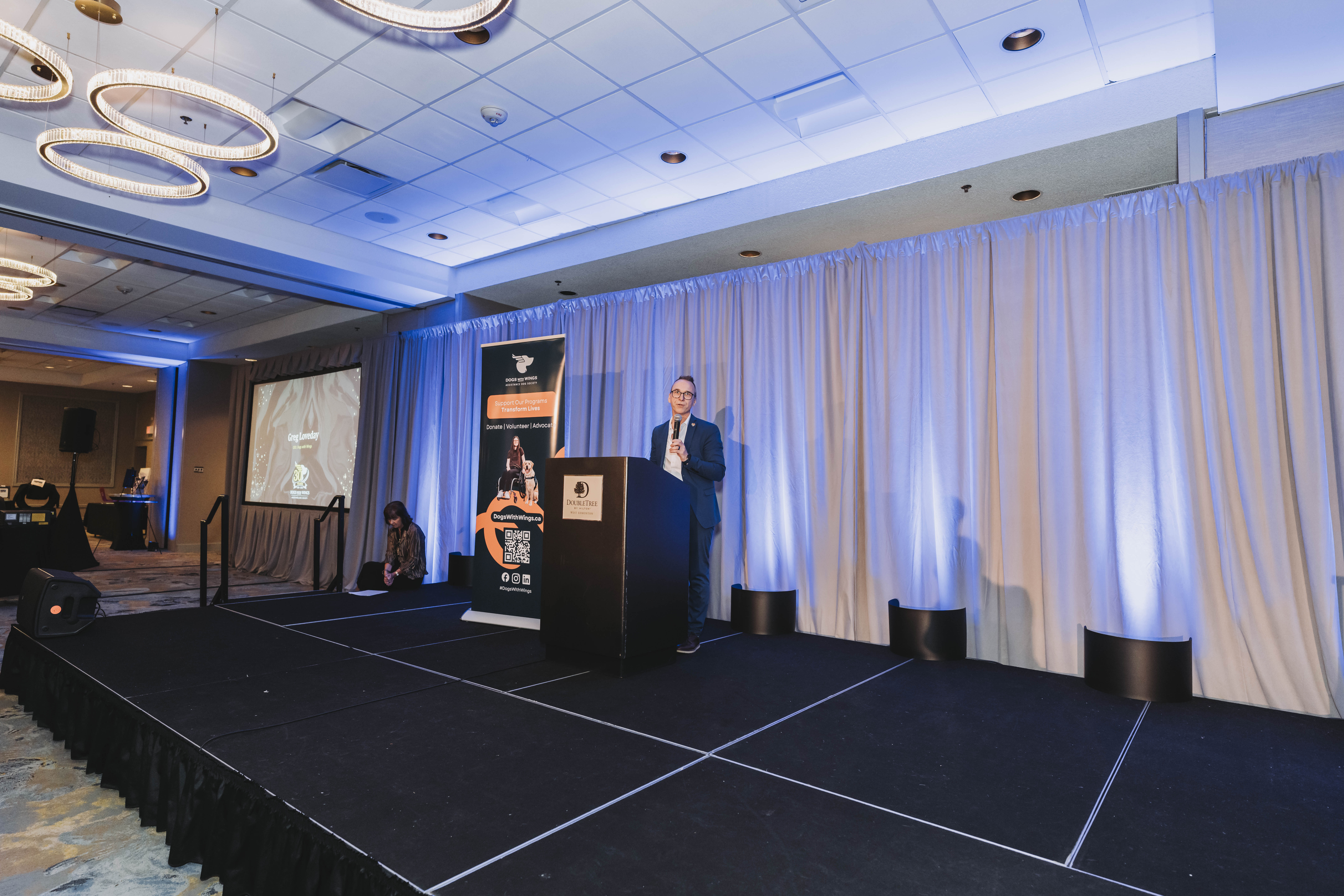 A guest presenting on stage beside the gala banner