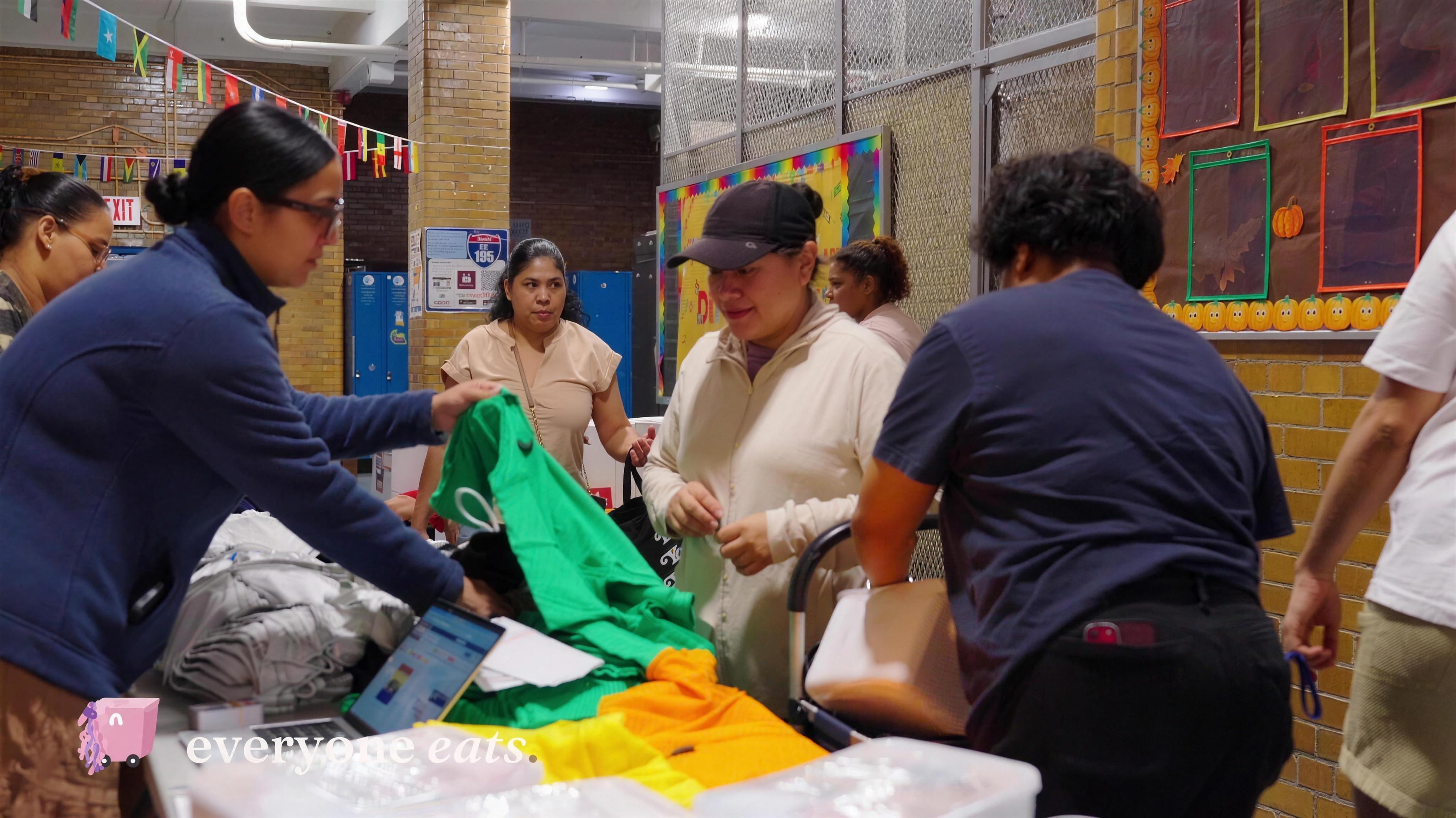 Community members selecting items from a table at a partner school event.