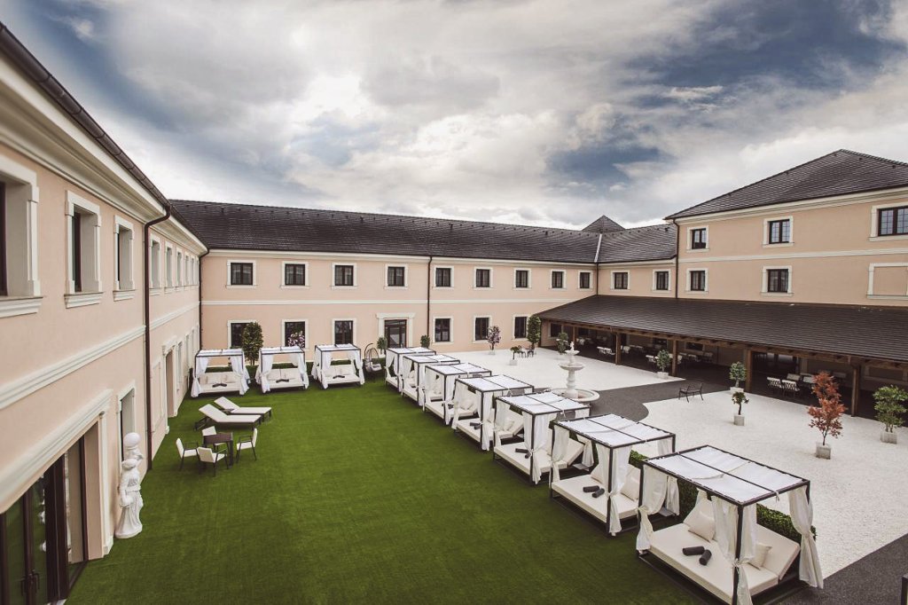 Nádvoří resortu Šanov s řadou zastřešených lounge postelí a umělým trávníkem