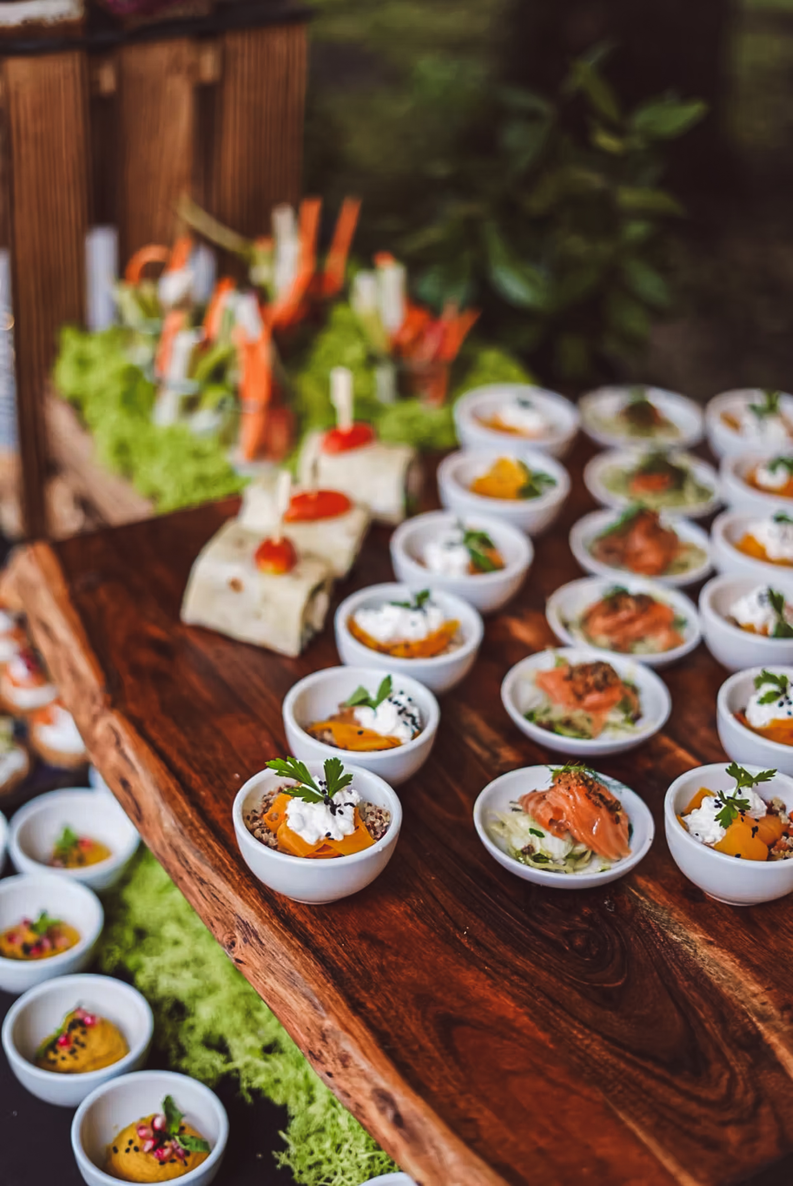 Elegantní mističky s cateringovými pochoutkami na dřevěném stole pro firemní akci