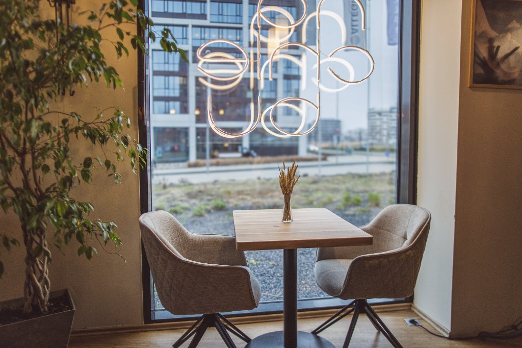 Stolek u okna s designovým závěsným svítidlem a sušenou pšenicí