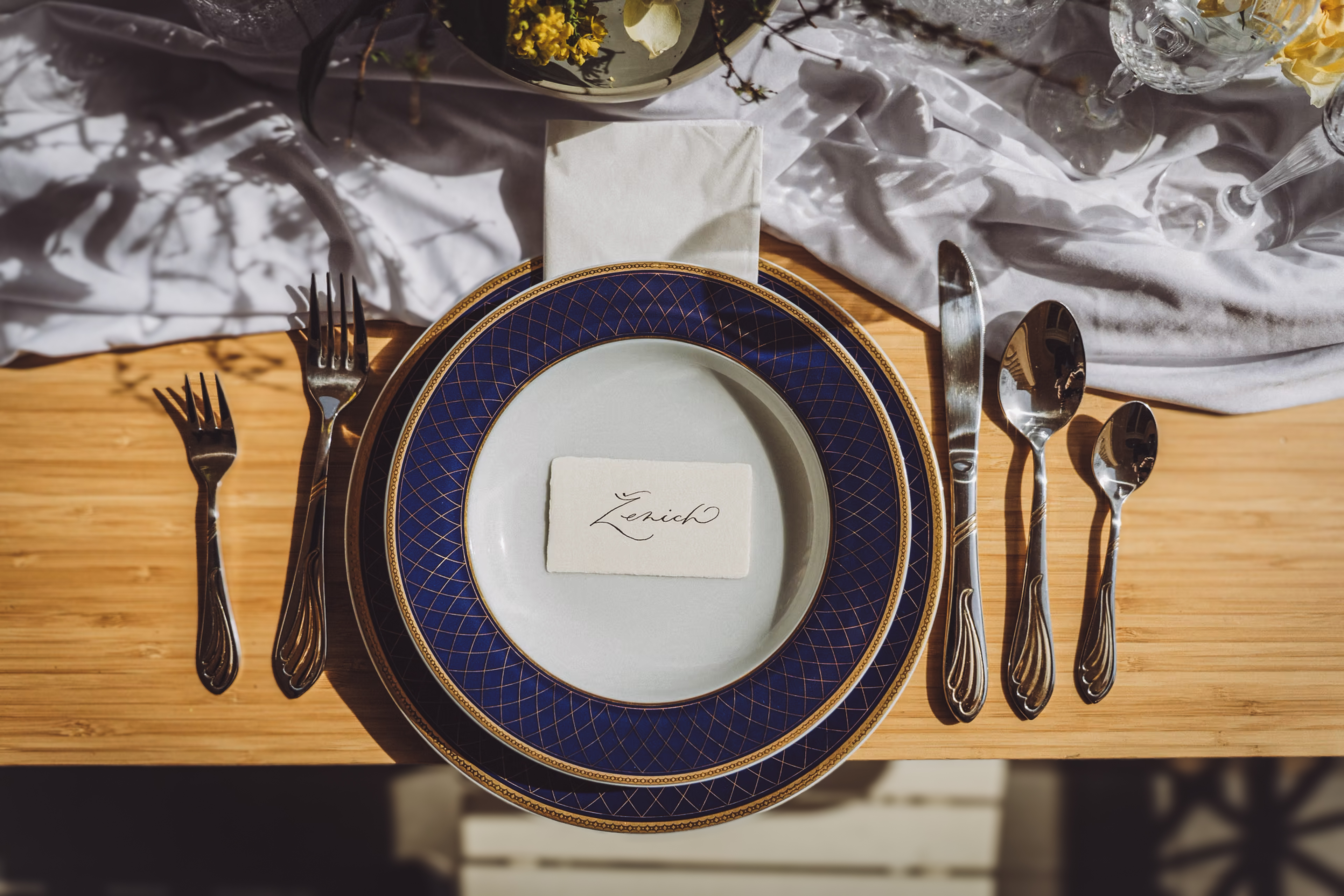 Elegantní svatební prostírání se jmenovkou hosta a modrozlatým talířem