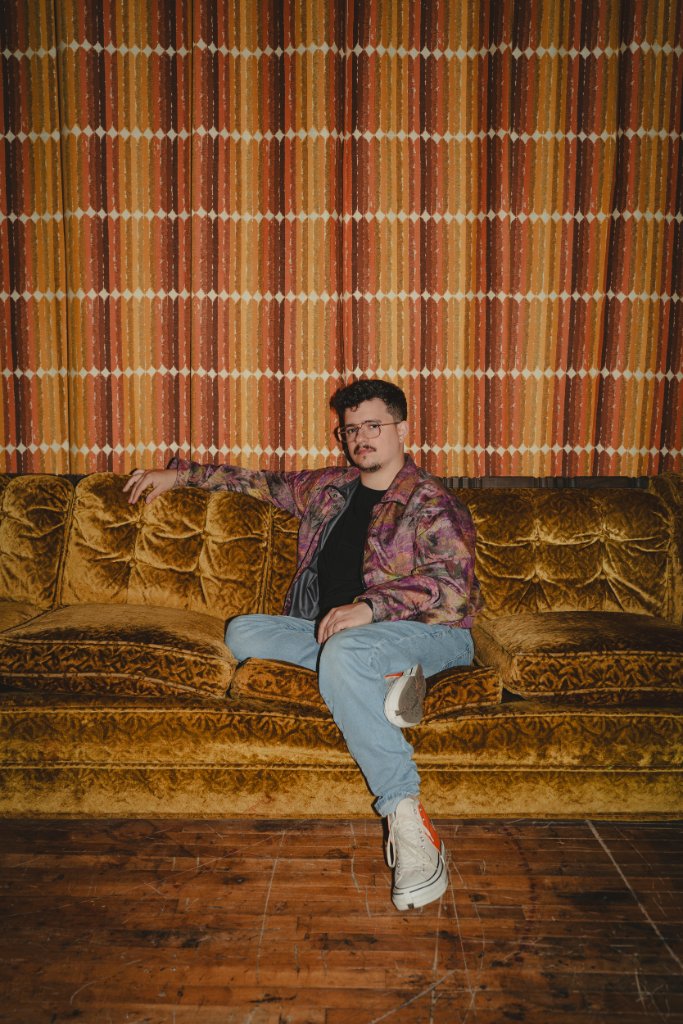 Vince Kelly seated on a vintage tufted couch
