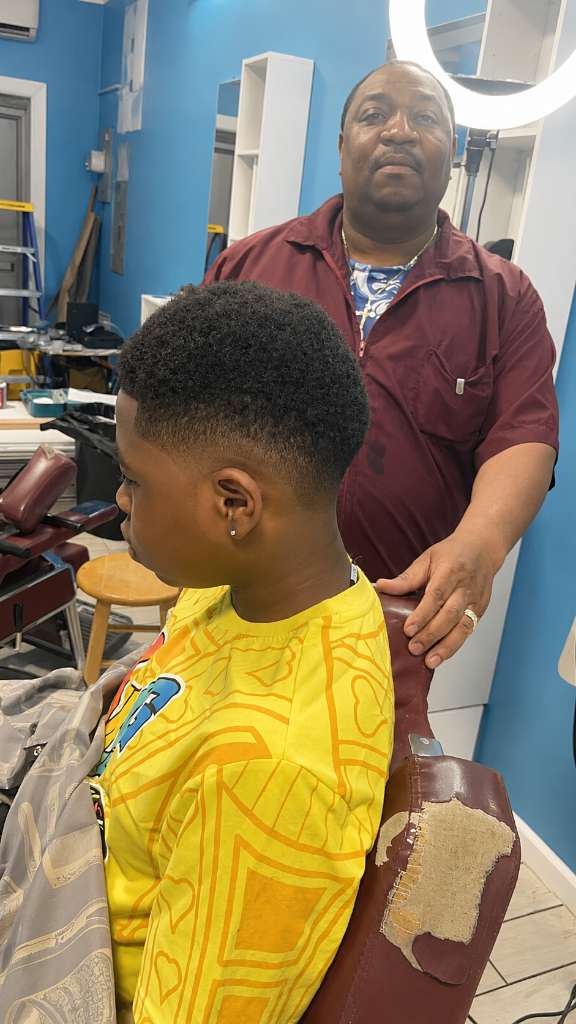 Barber showcasing fresh haircut on young client