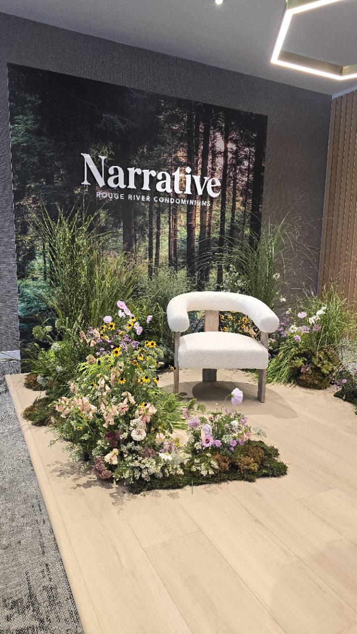 Angled view of the Narrative forest backdrop, cream chair and floral arrangements on a wood-look platform.