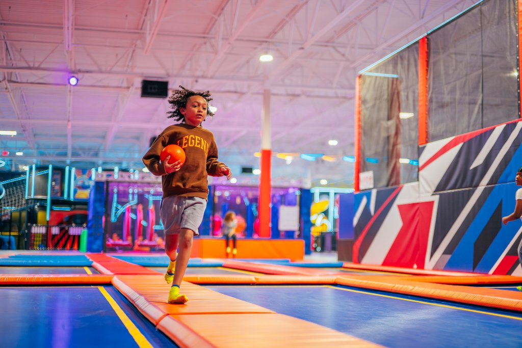 Child running with dodgeball on trampoline court at Lululand Adventure Park