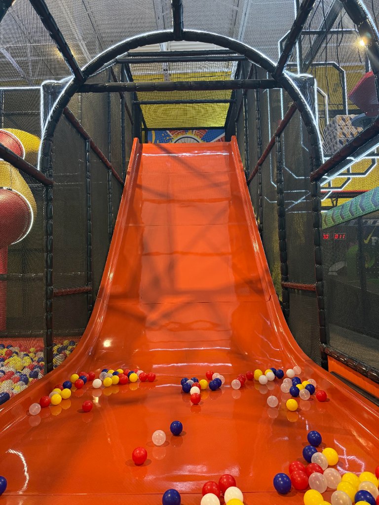 Orange slide plunging into a colorful ball pit at Lululand Adventure Park