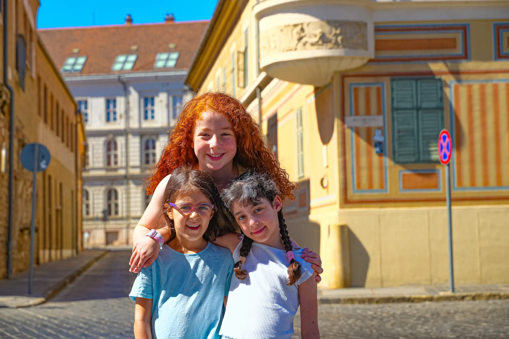 Kids photo session Budapest — three children in colorful Castle District street