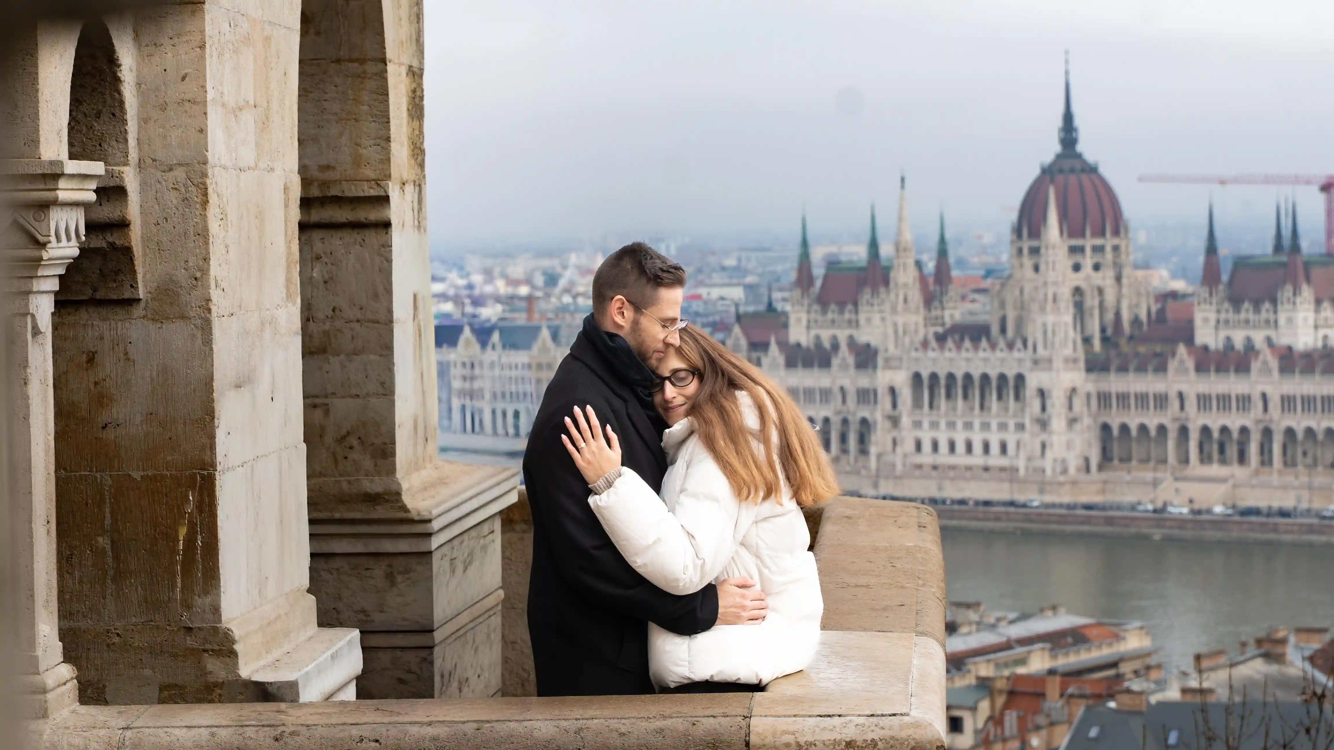 Surprise proposal photographer Budapest — couple at Fisherman's Bastion with Parliament view
