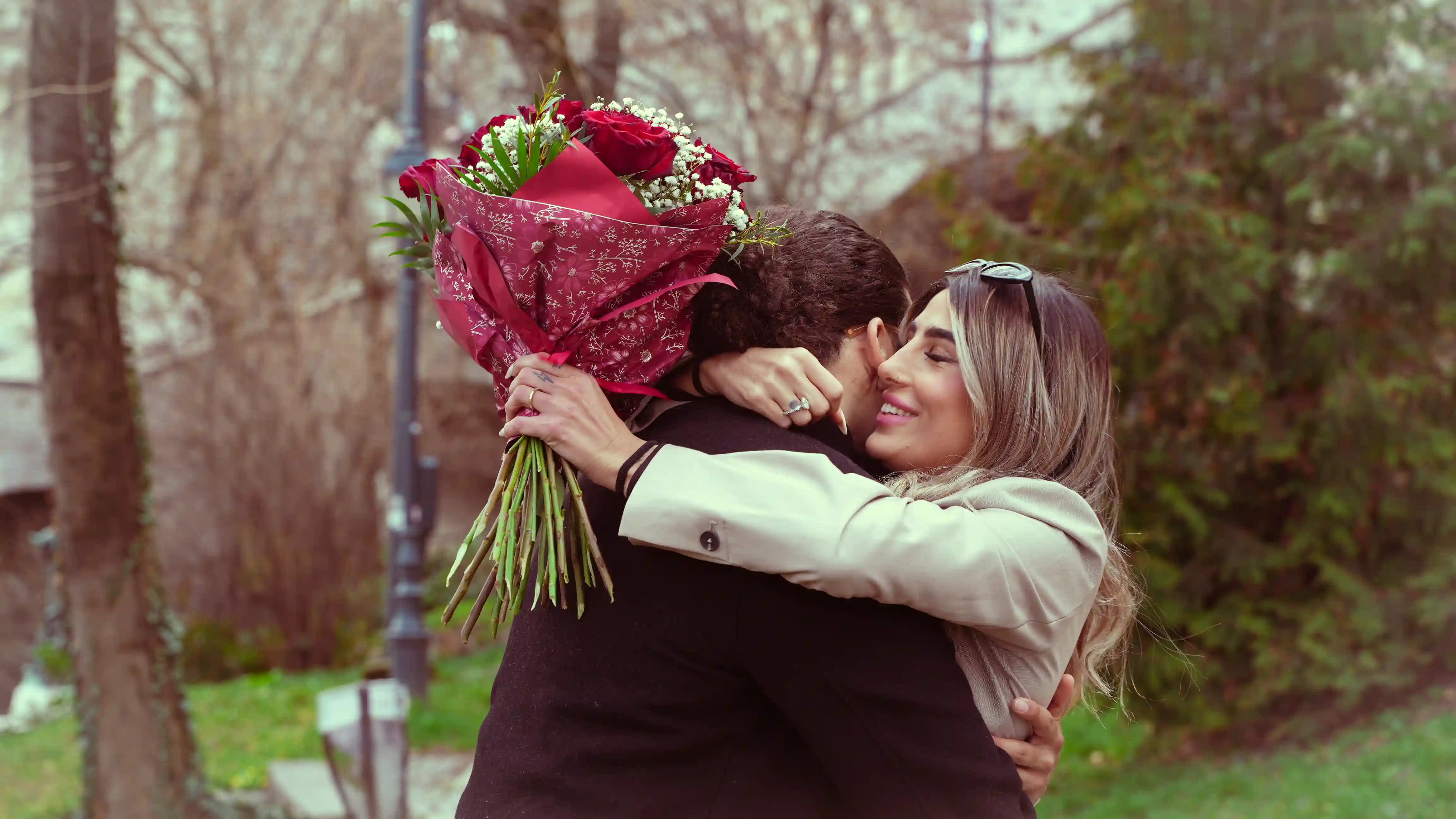 Proposal photography Budapest — couple embracing with red roses bouquet