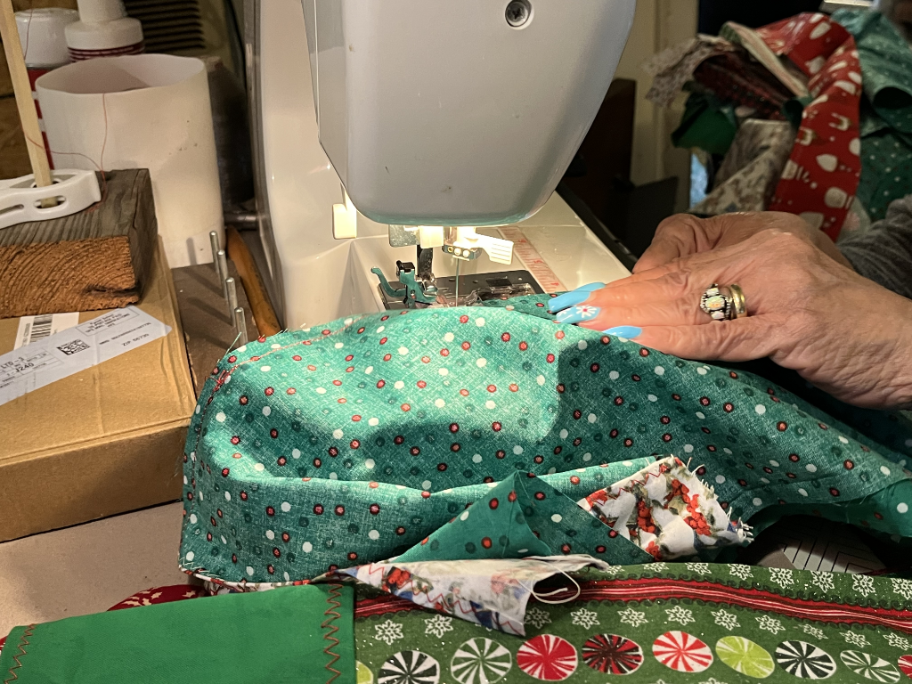 Close-up of a Singer sewing machine stitching festive green fabric