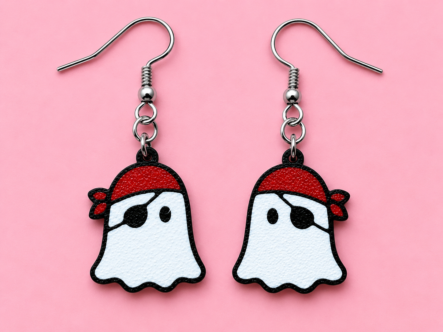 White ghost earrings with black outlines, red bandanas and black eye patches on a pink background