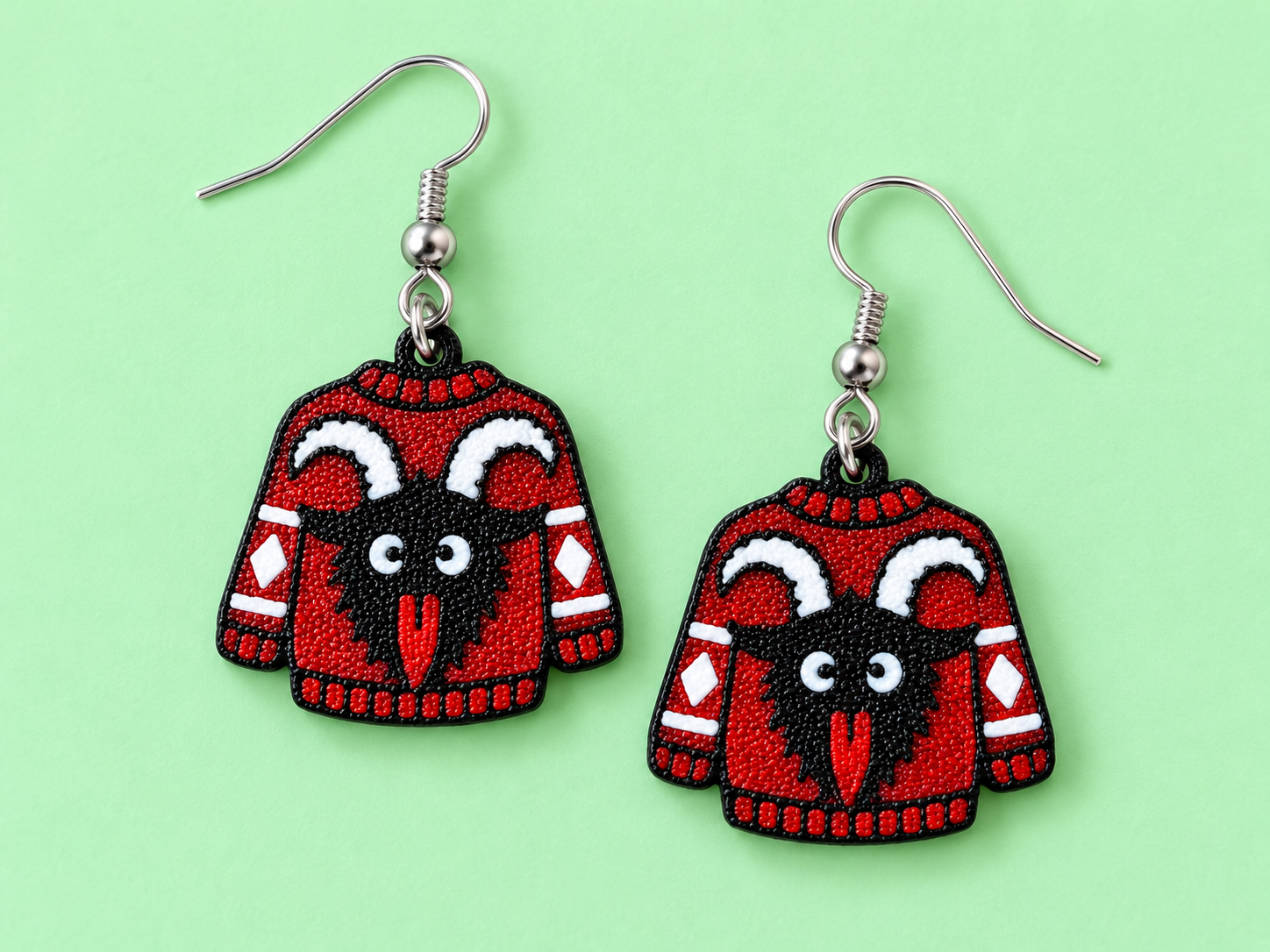 Red Christmas sweater earrings with a black horned Krampus creature and white striped sleeves
