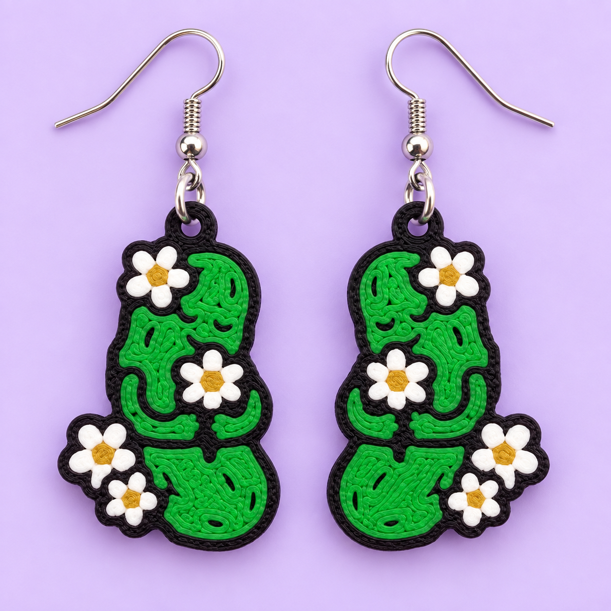 Bright green pickle earrings decorated with white daisies and yellow centers, outlined in black, on a lavender background