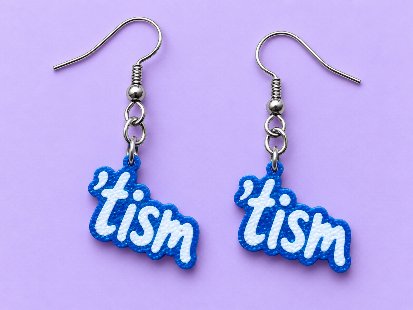 Sparkly royal blue earrings spelling the word tism in raised white bubble letters