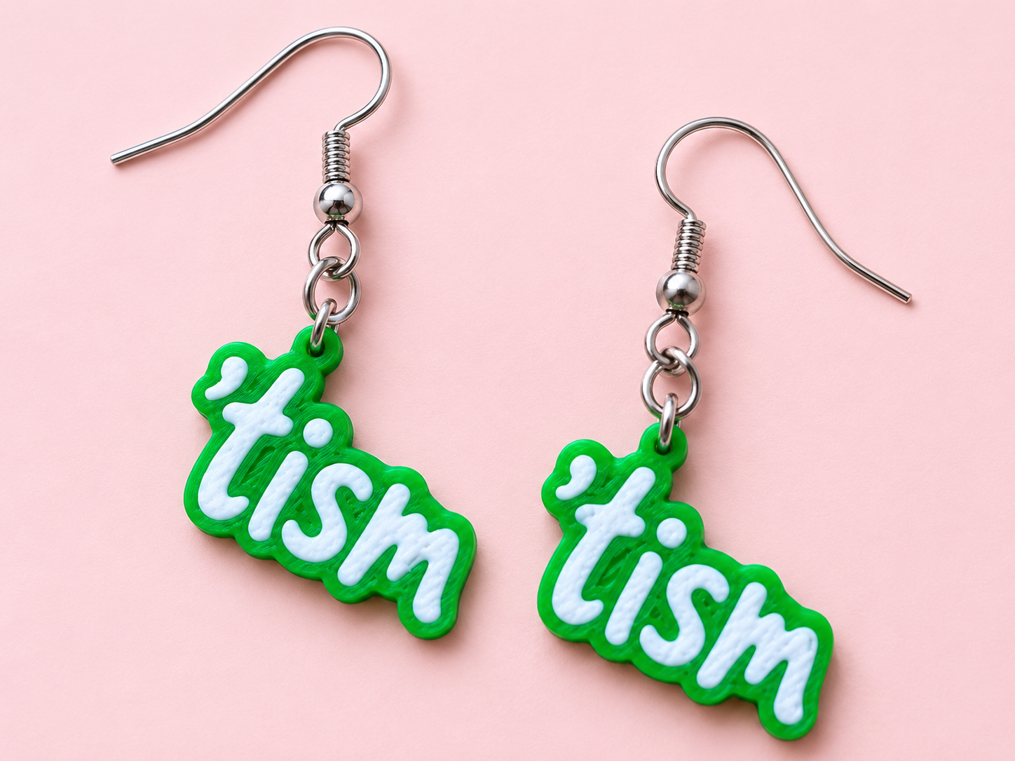 Green earrings spelling the word tism in raised white bubble letters