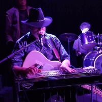 Tom Phelps playing pedal steel guitar on stage in a black cowboy hat
