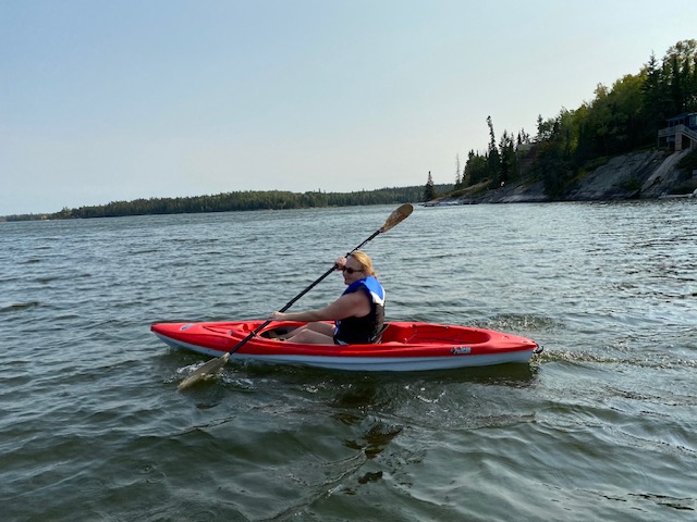 A kayaker paddling a red kayak on Gunn Lake