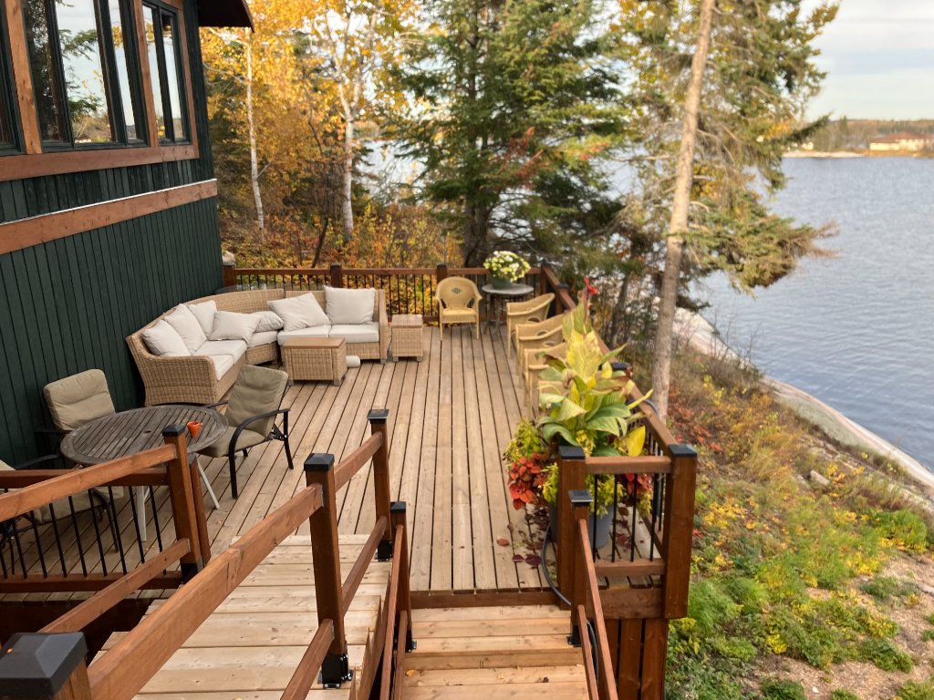 Side deck lounge with a wicker sectional and autumn shoreline views at Gunn Lake Lodge