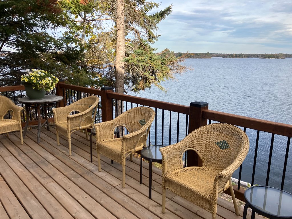 Wicker chairs on a cedar deck overlooking Gunn Lake at Gunn Lake Lodge