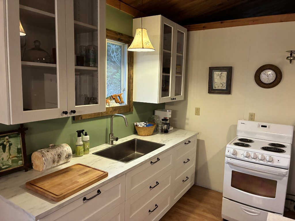 Cottage kitchen with marble-look counters, white cabinets, and electric stove