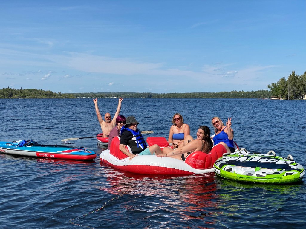 Guests floating and paddleboarding on Gunn Lake on a sunny summer day
