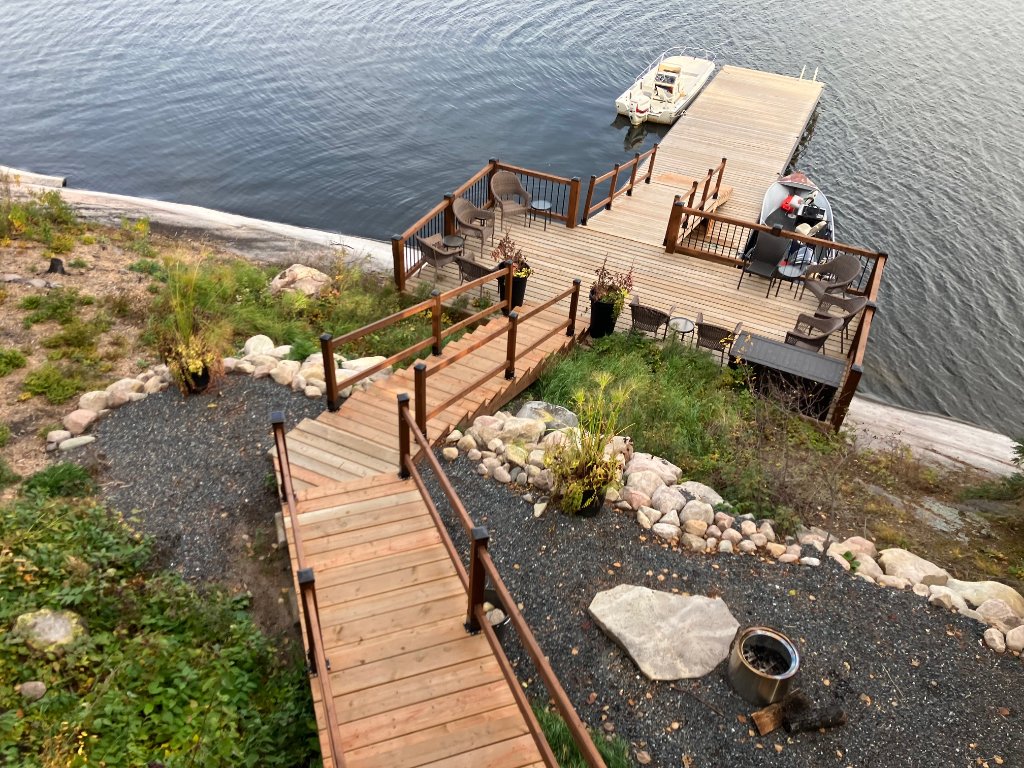 Aerial view of the main dock, boats, and cedar shoreline stairs at Gunn Lake Lodge