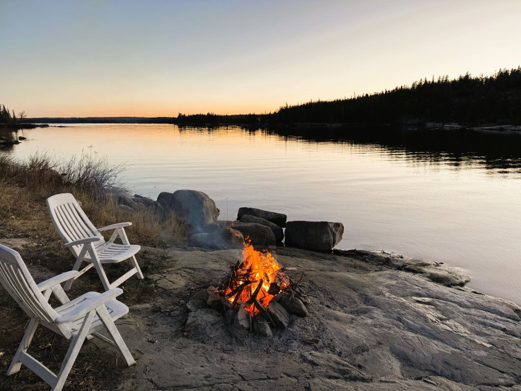 Campfire on the rocks beside Gunn Lake at sunset at Kendall's Point, Minaki, Ontario