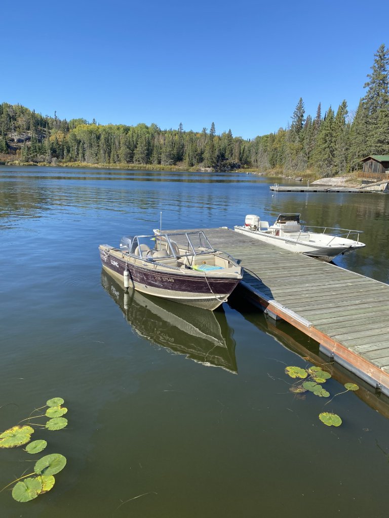 Two boats moored at the dock on a calm clear day on Gunn Lake