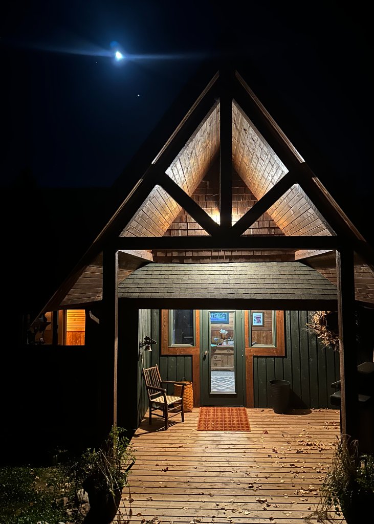 The lit gable entryway of Gunn Lake Lodge at night under a bright moon