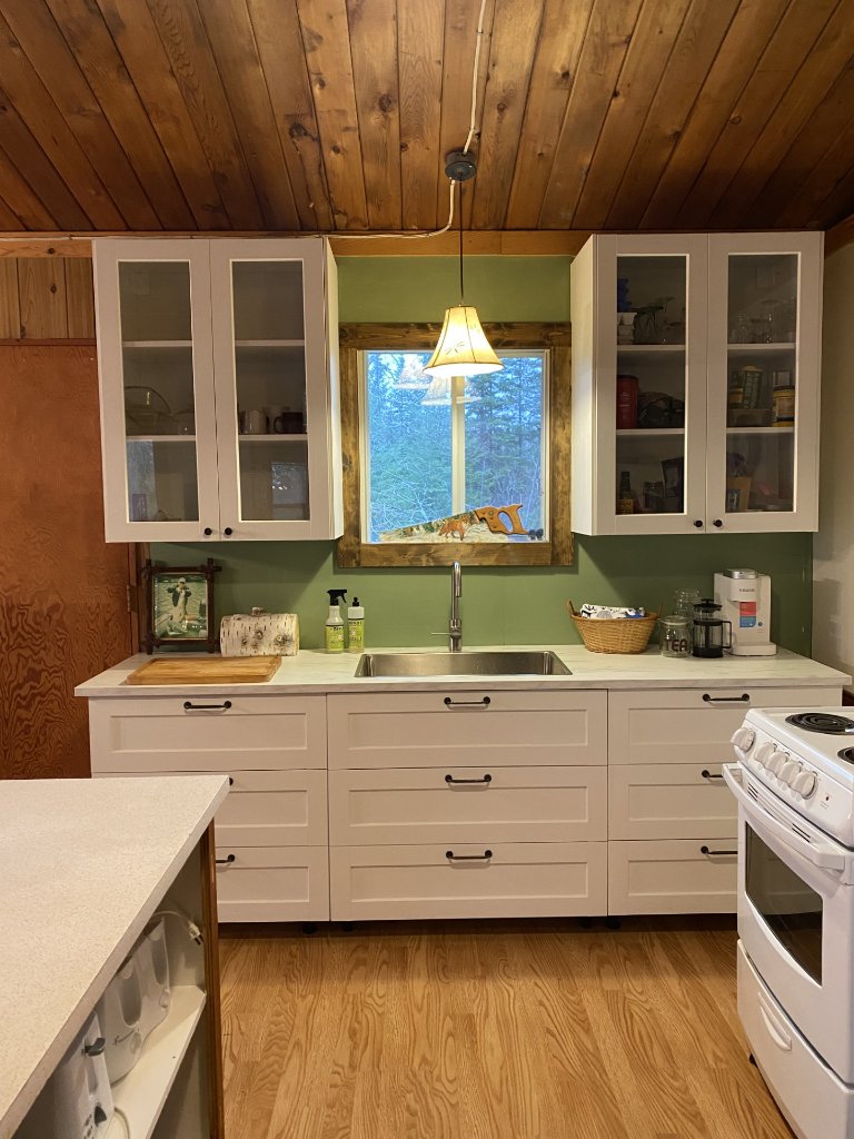 Bright white cottage kitchen with green walls and a window over the sink