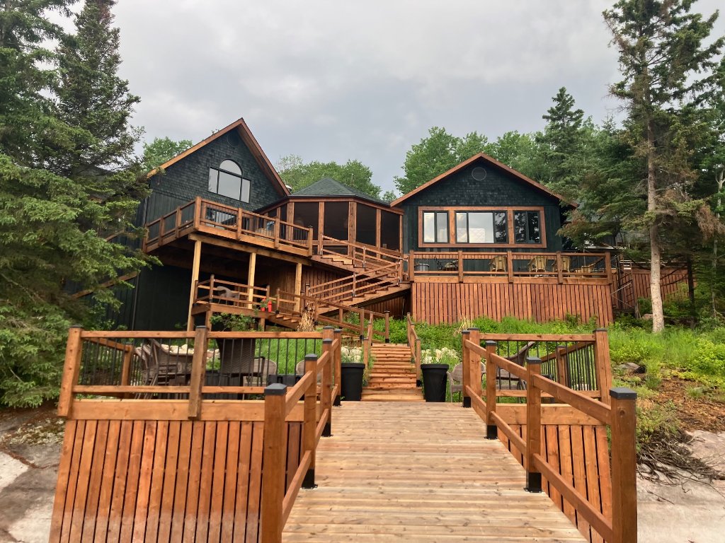 Gunn Lake Lodge exterior with tiered cedar decks, stairs, and landscaped stone gardens