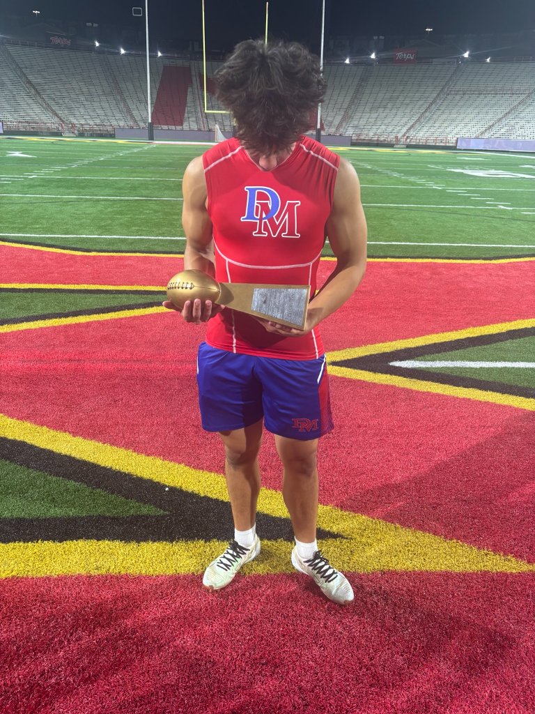 Austin Barber holding a gold football award at DeMatha