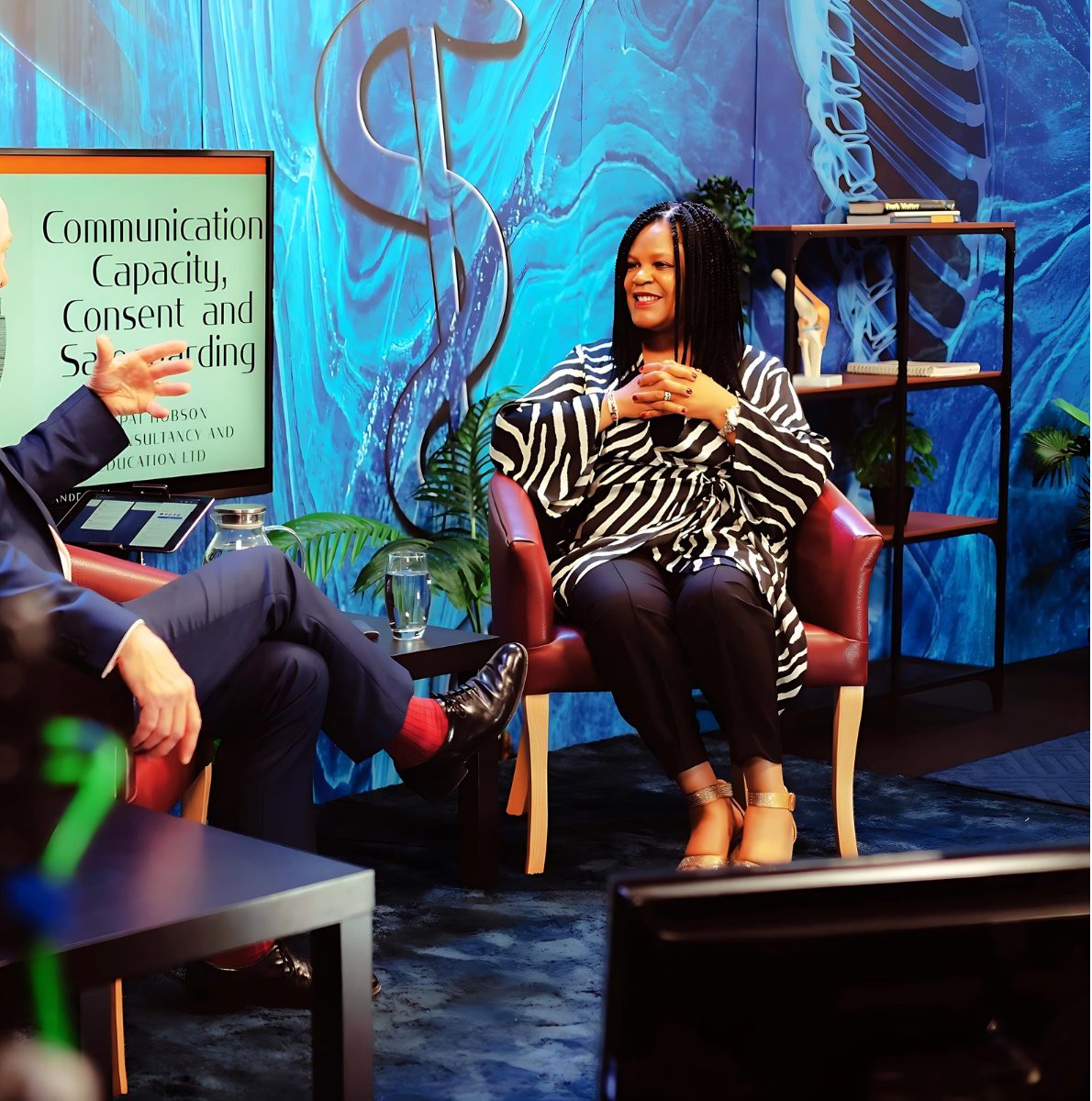 Pat Hobson in conversation in a studio, with the title Communication, Capacity, Consent and Safeguarding on screen