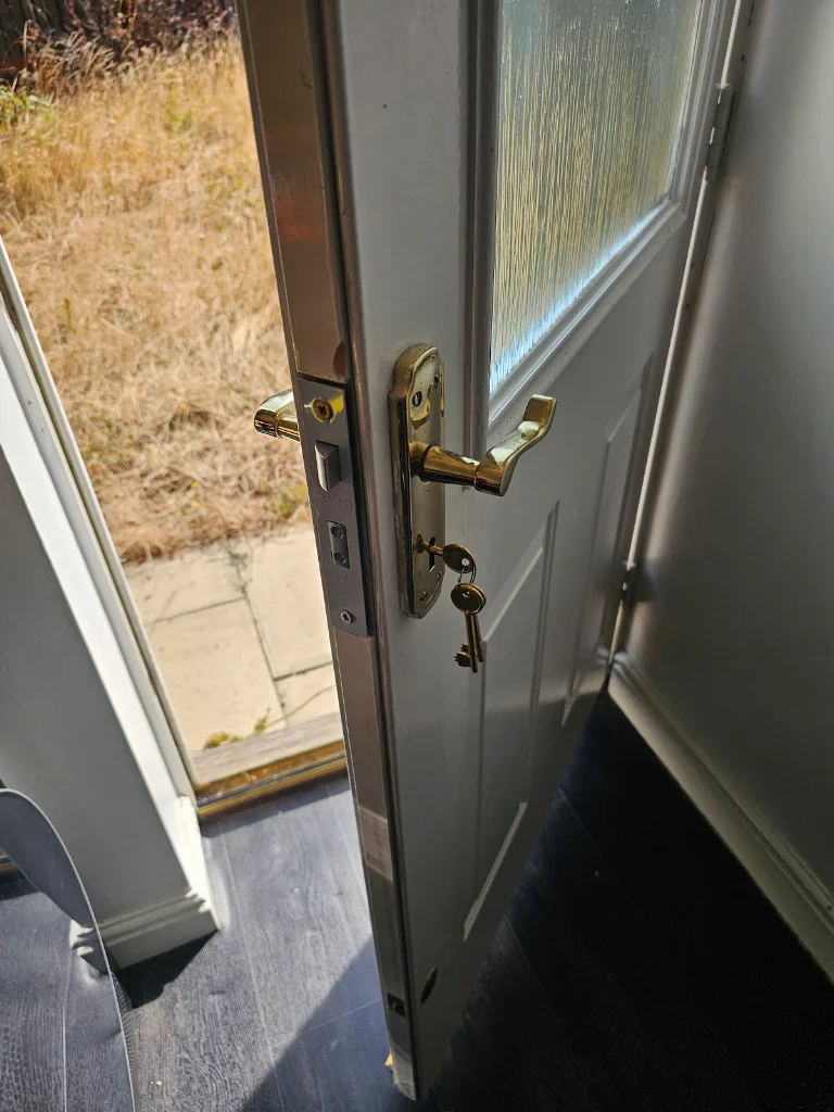 White uPVC patio door edge with new brass handle set and lock, key in use, fitted by SIDE Locksmiths