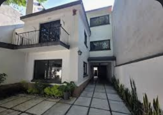 Casa blanca con corredor cubierto y jardinera ornamental
