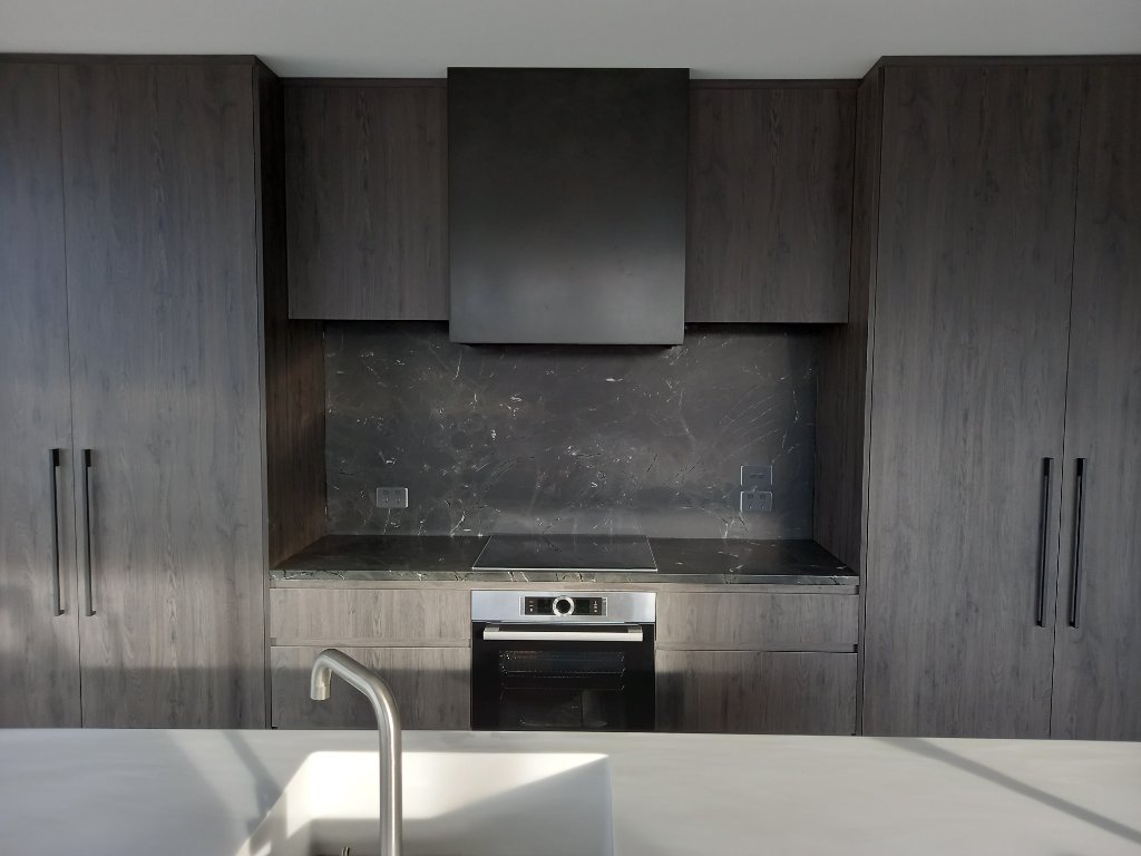 Dark kitchen with marble splashback and rangehood