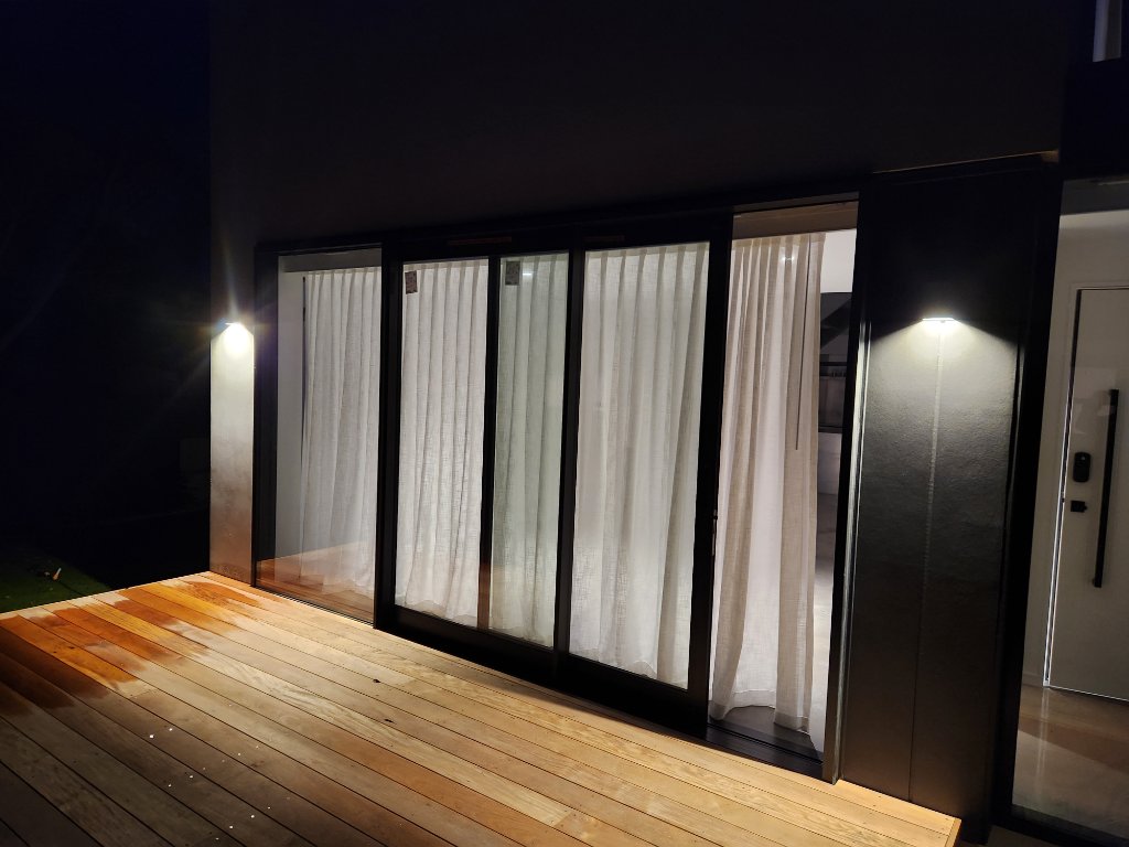 Deck with sliding doors and wall lighting at night