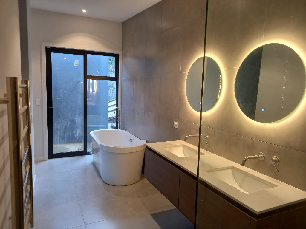 Bathroom with freestanding tub and backlit mirrors