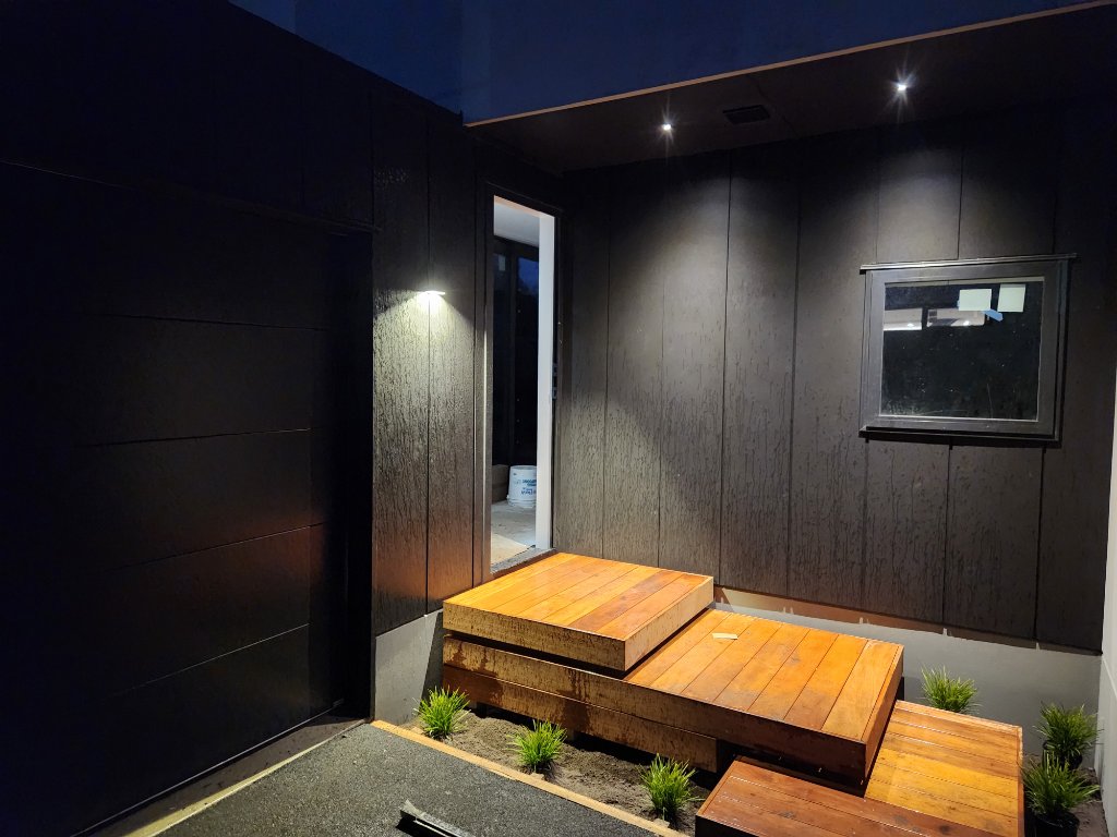 Entryway with wood deck steps and feature lighting at night
