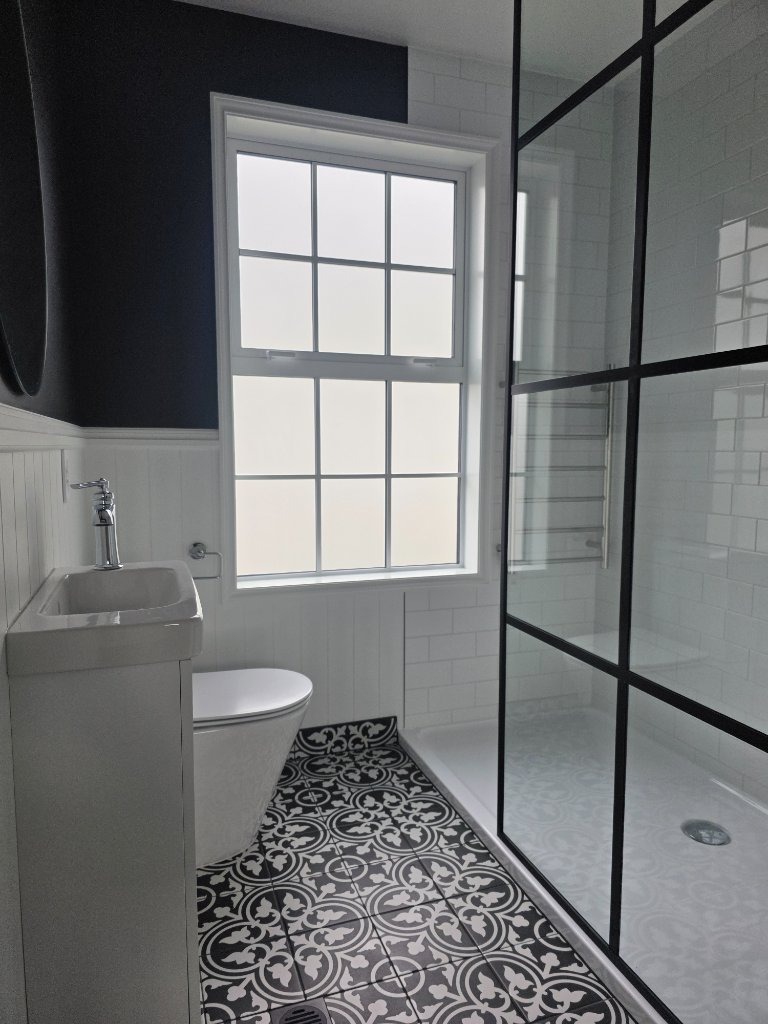 Bathroom with patterned tile floor and black framed shower