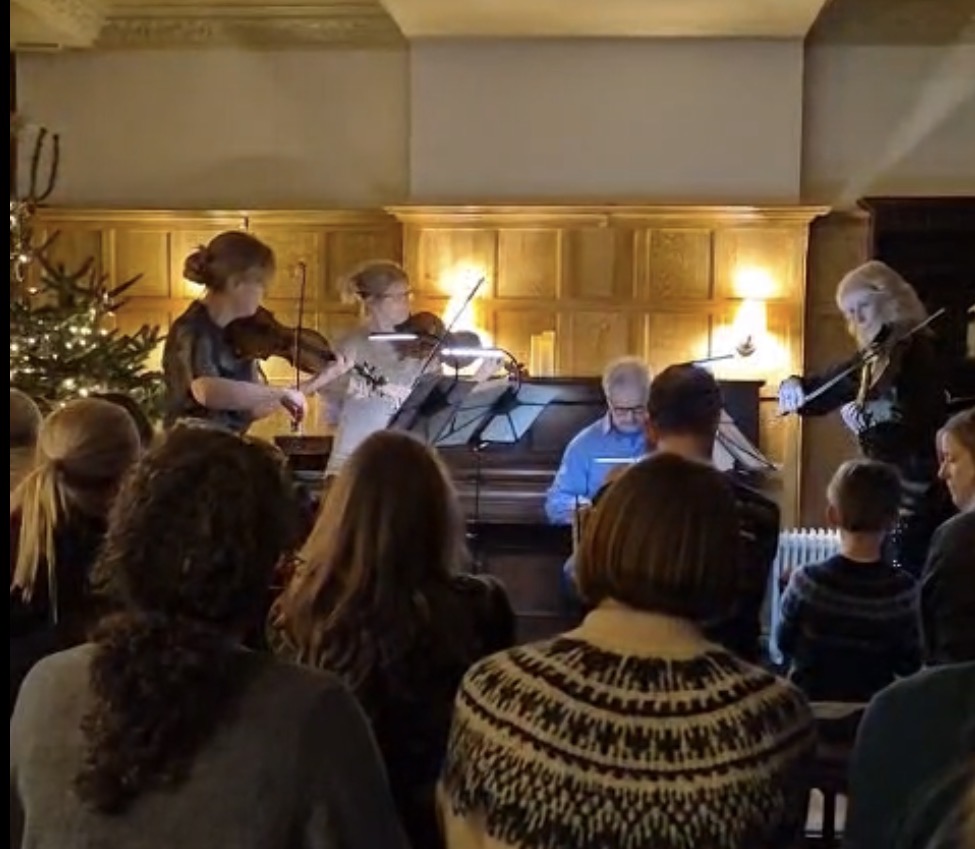 Christmas concert with violinists and pianist performing to a packed audience