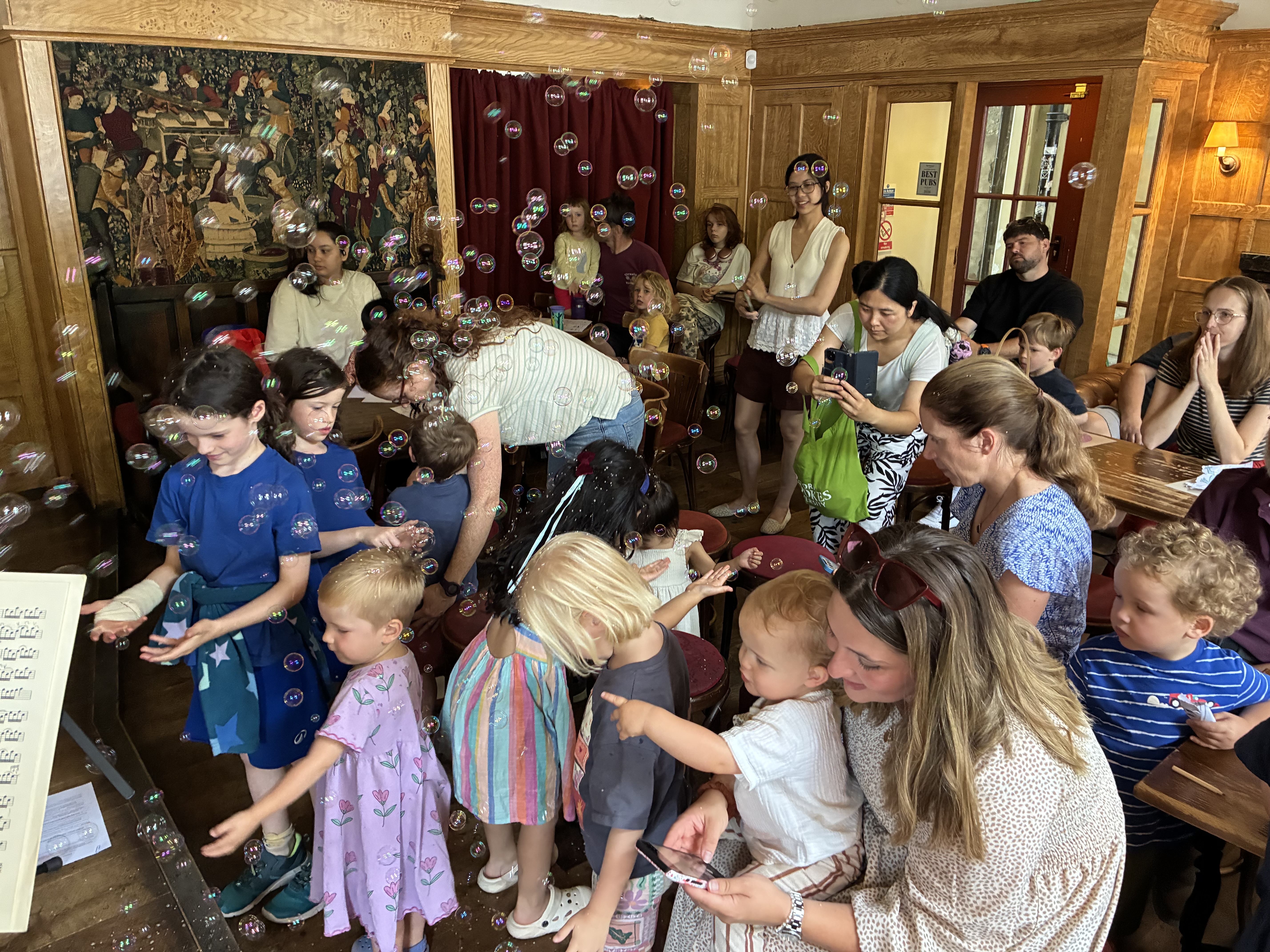 Children and adults enjoying bubbles at a Tinklings family concert in the Flag Room