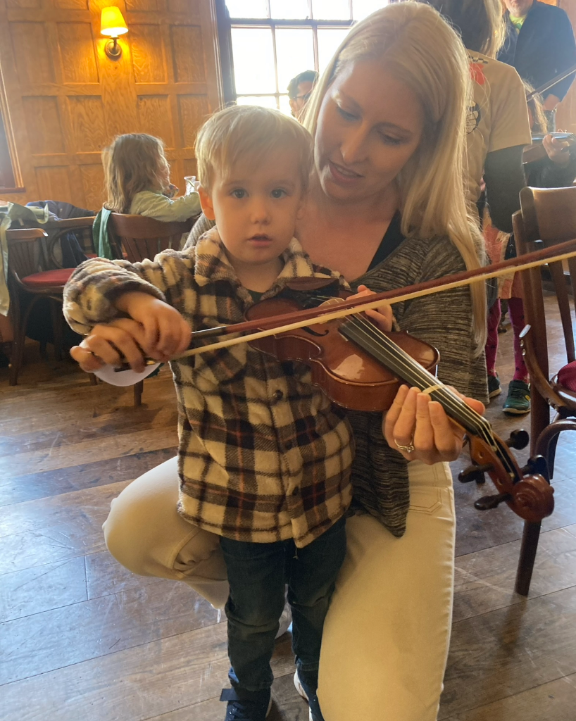 A small boy and a woman with a violin at a Tinklings children's event