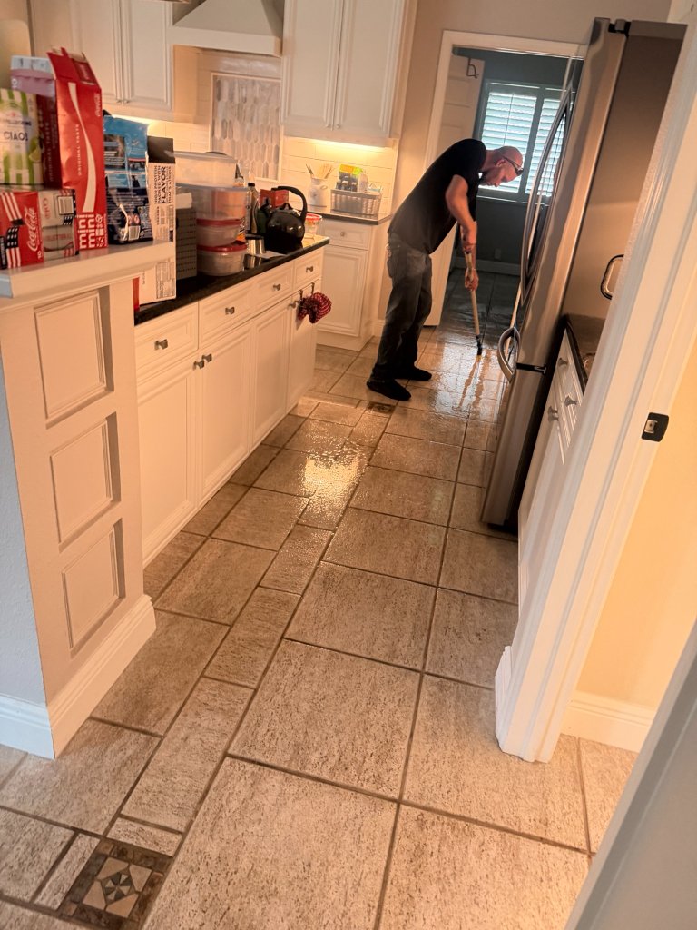 Technician deep cleaning kitchen tile floor with professional wand in Florida home